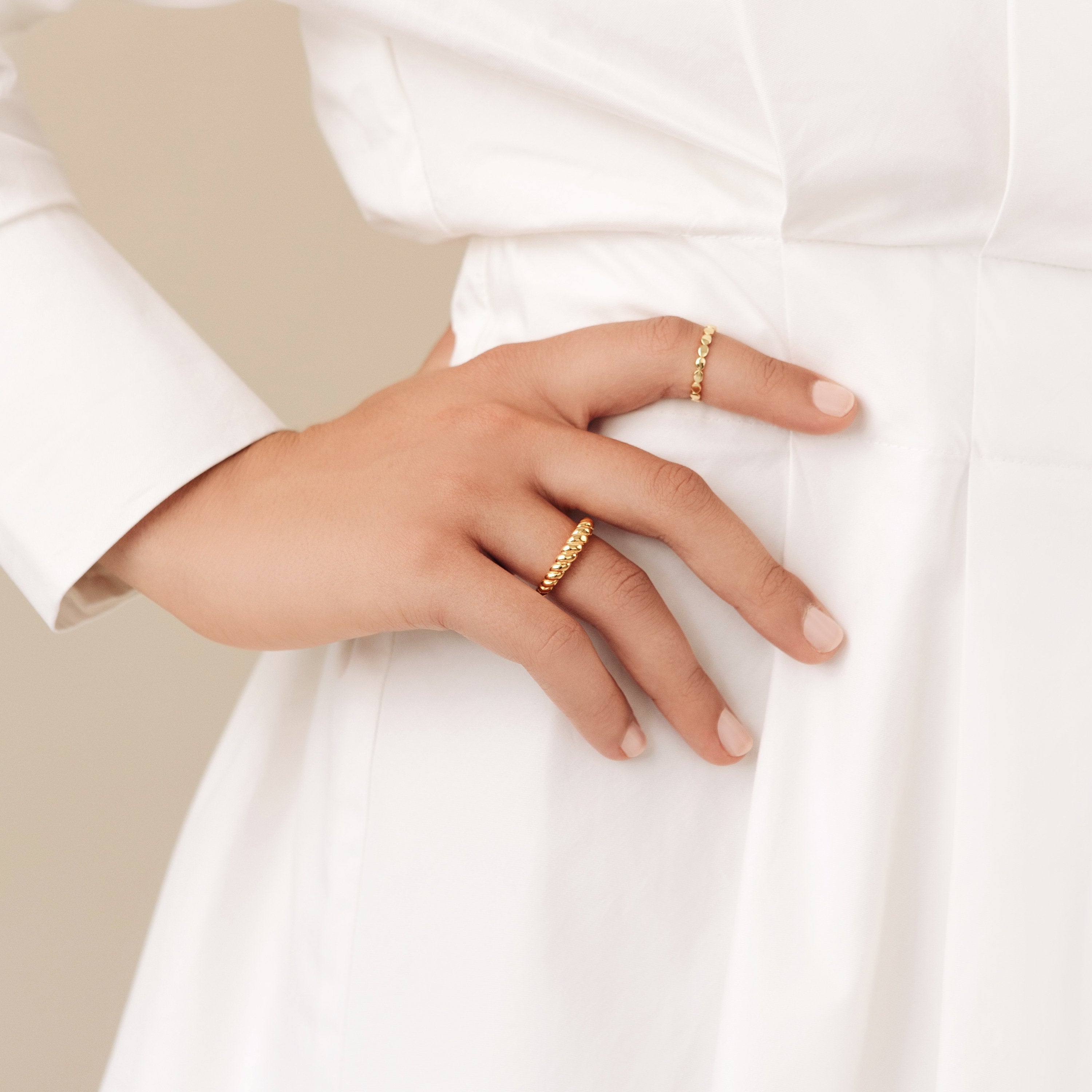 A hand wearing the Twisted Dome Ring rests gently on the waist of a person in a white dress.