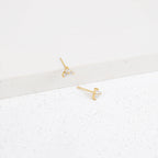 Lily Studs: Gold earrings featuring three small clear stones each, perfect for stacking. Displayed on a white textured surface.