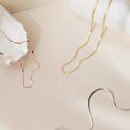 Gold, rose gold and silver herringbone necklaces arranged in a flat lay