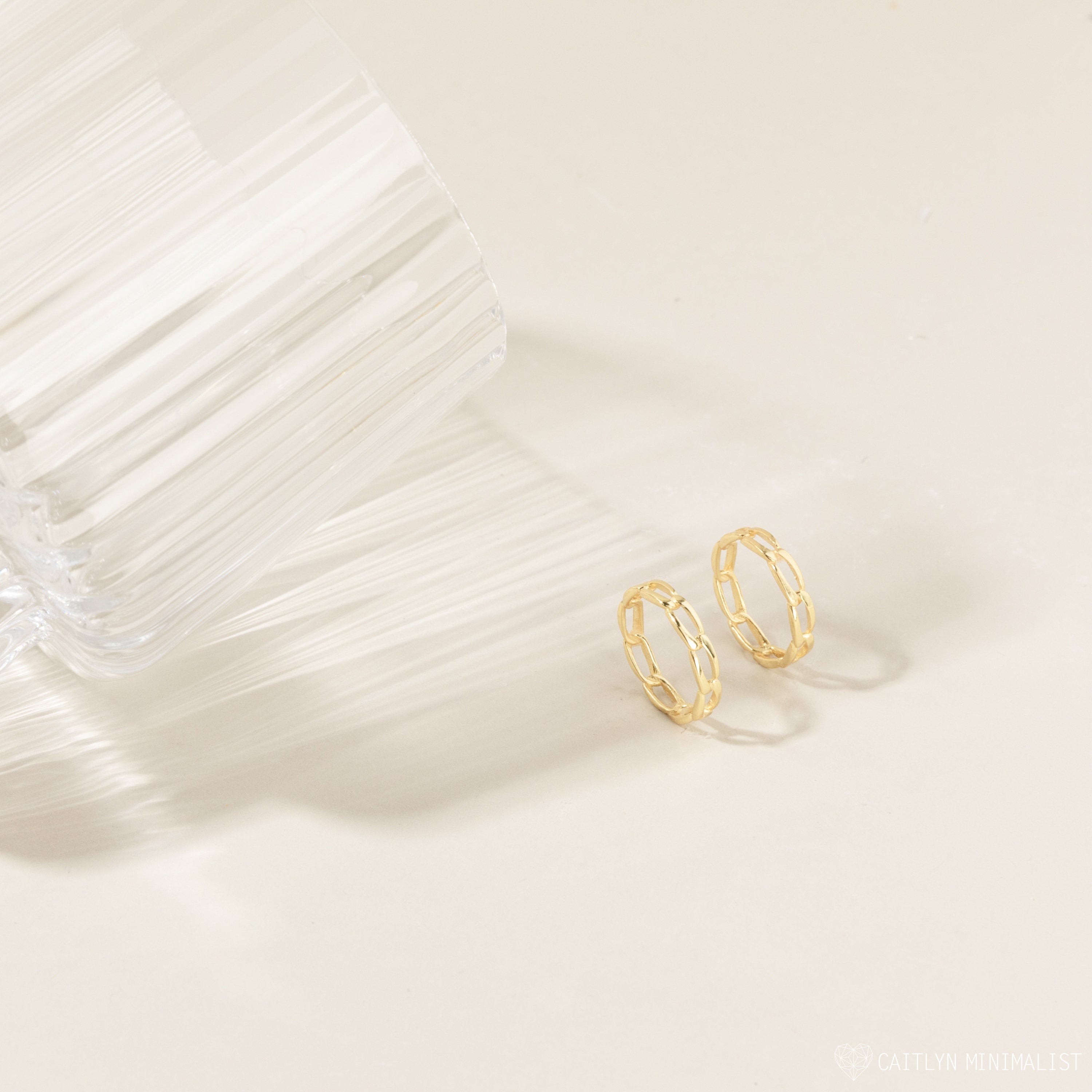 Pair of the gold link rings placed closely together on a fabric backdrop, highlighting the linked design and muted gold tone.