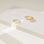 Three of our gold Dome Rings displayed on a minimalist white block with soft natural lighting, showcasing their smooth, polished finish.