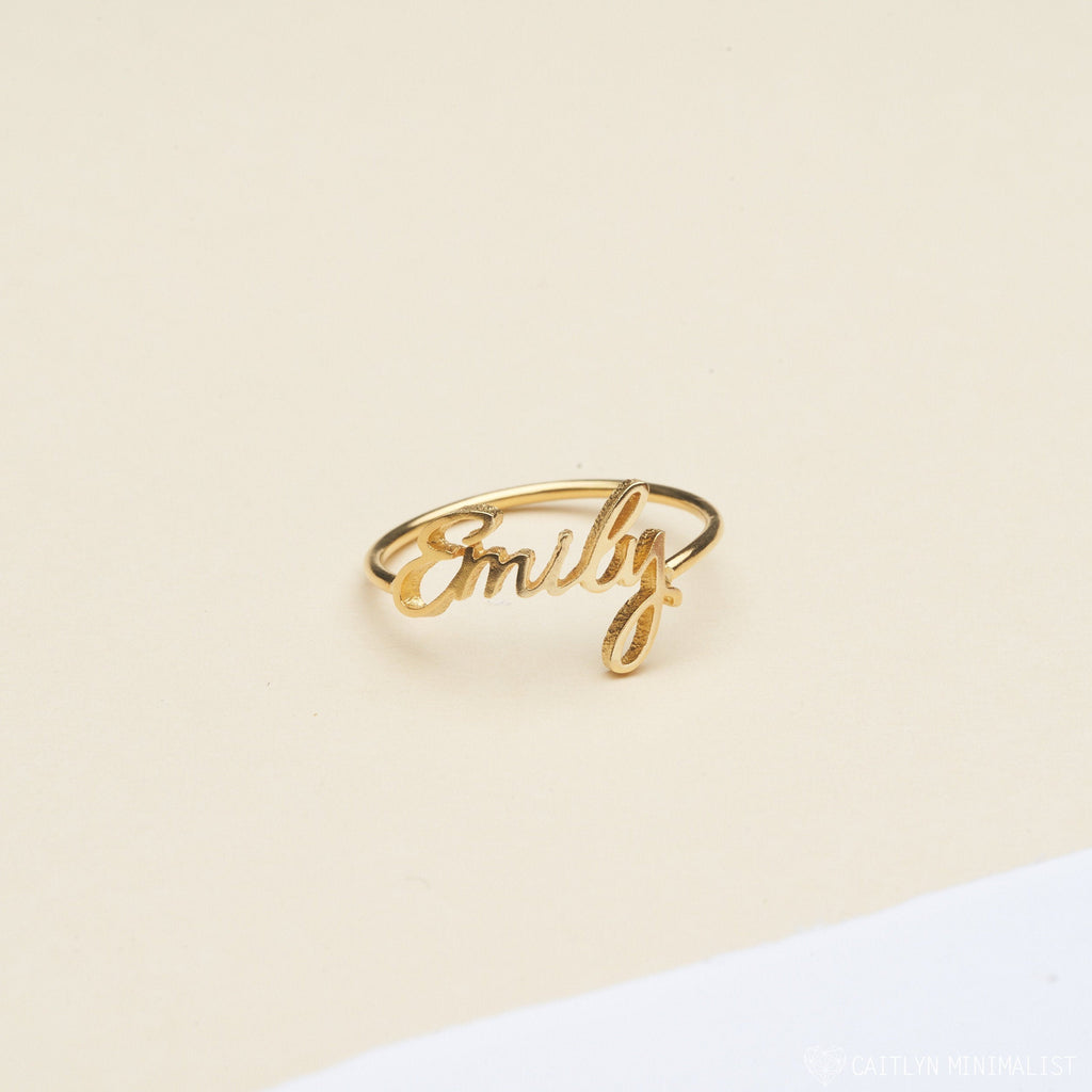 The Grace Script Name Ring features the name Emily in elegant cursive on a cream and white background.