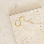 The Large Sideways Initial Necklace features a bold gold letter pendant, beautifully showcased on a textured light stone—making it a standout statement piece.