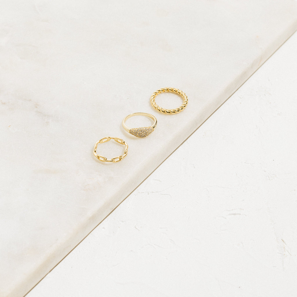 The Pave Signet Ring is showcased with two other gold rings on a marble surface against a white background, creating a chic modern-luxe accessory set.