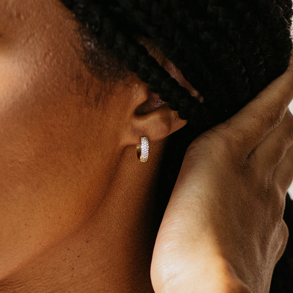 Close-up of a person wearing Pave Diamond Huggies, hand touching their ear—a true jewelry box essential.