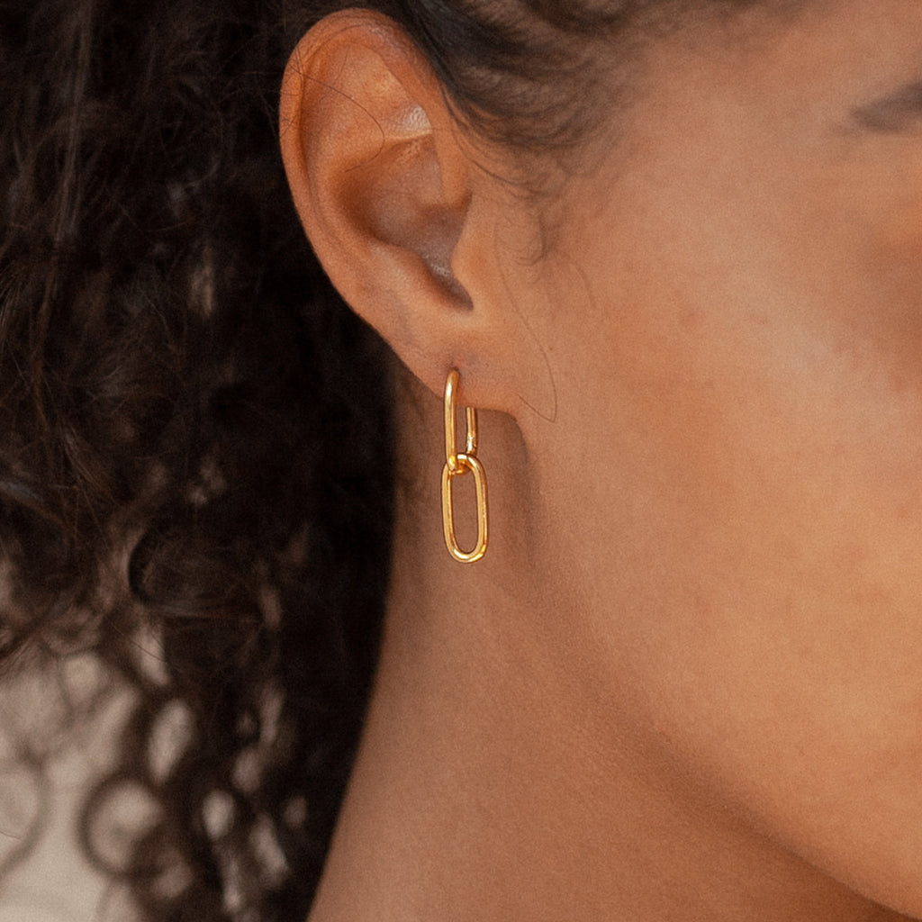 Close-up of a person wearing Amanda Link Earrings in 18K Gold, featuring elegant minimal hoops with elongated oval links.