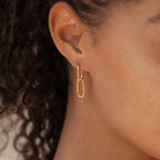 Close-up of a person wearing Amanda Link Earrings in 18K Gold, featuring elegant minimal hoops with elongated oval links.