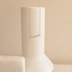 The Pave Mama Script Necklace features a sparkling cursive pendant, elegantly displayed on a smooth, cream-colored ceramic vase—an ideal piece of motherhood jewelry and the perfect gift for Mom.