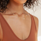 Woman wearing the Pave Mama Letter Necklace and a rust-colored sleeveless top—the perfect motherhood jewelry piece.
