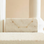 The Pave Mama Letter Necklace, shown with small charms on a marble block and neutral background, is a stylish piece of motherhood jewelry—making it the perfect gift for mom.