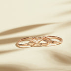 Three Skinny Zodiac Rings with engraved astrological signs are stacked on a light surface, creating subtle shadows.