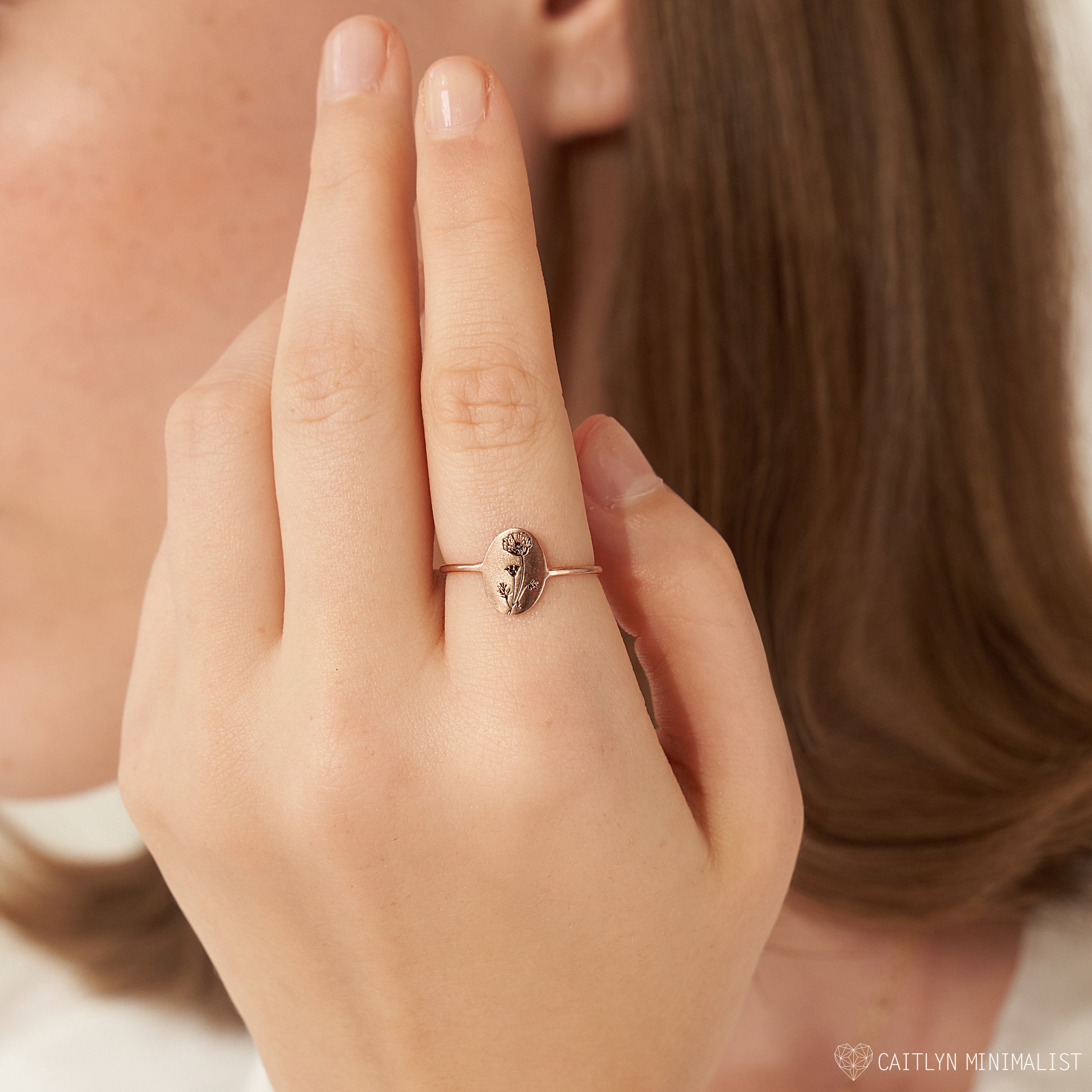 Close-up of a woman wearing the Birth Flower Oval Ring with a leaf design, hand near her face. Perfect for those who love personalized jewelry.