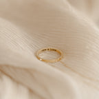 The Inner Circle Necklace, engraved with SAM & LIAM, rests on a soft, cream-colored fabric background, evoking the sentiment of a treasured amulet.