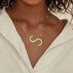 A woman wears a white shirt and the Large Sideways Initial Necklace in Rose Gold, featuring a bold letter pendant that makes it a true statement piece.