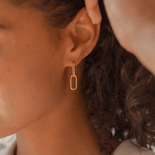 Close-up of a person wearing Amanda Link Earrings in 18K Gold, with curly hair partially visible.