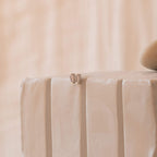 A pair of Baguette Diamond Studs, small and subtle, rest elegantly on the edge of a textured white surface.