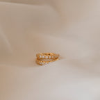 The Vera Pave Huggies are displayed on a soft beige fabric background, ideal for pairing with minimalist earrings or other everyday jewelry.