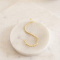 The Essential Bracelet Chains, featuring a gold rope design with polished finishes, are displayed on a round white marble tray.