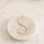 The Essential Bracelet Chains, featuring a gold rope design with polished finishes, are displayed on a round white marble tray.