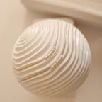 Gold and Rose Gold Pearl Bead Necklaces displayed on a white sculptural object with curved, ridged texture.