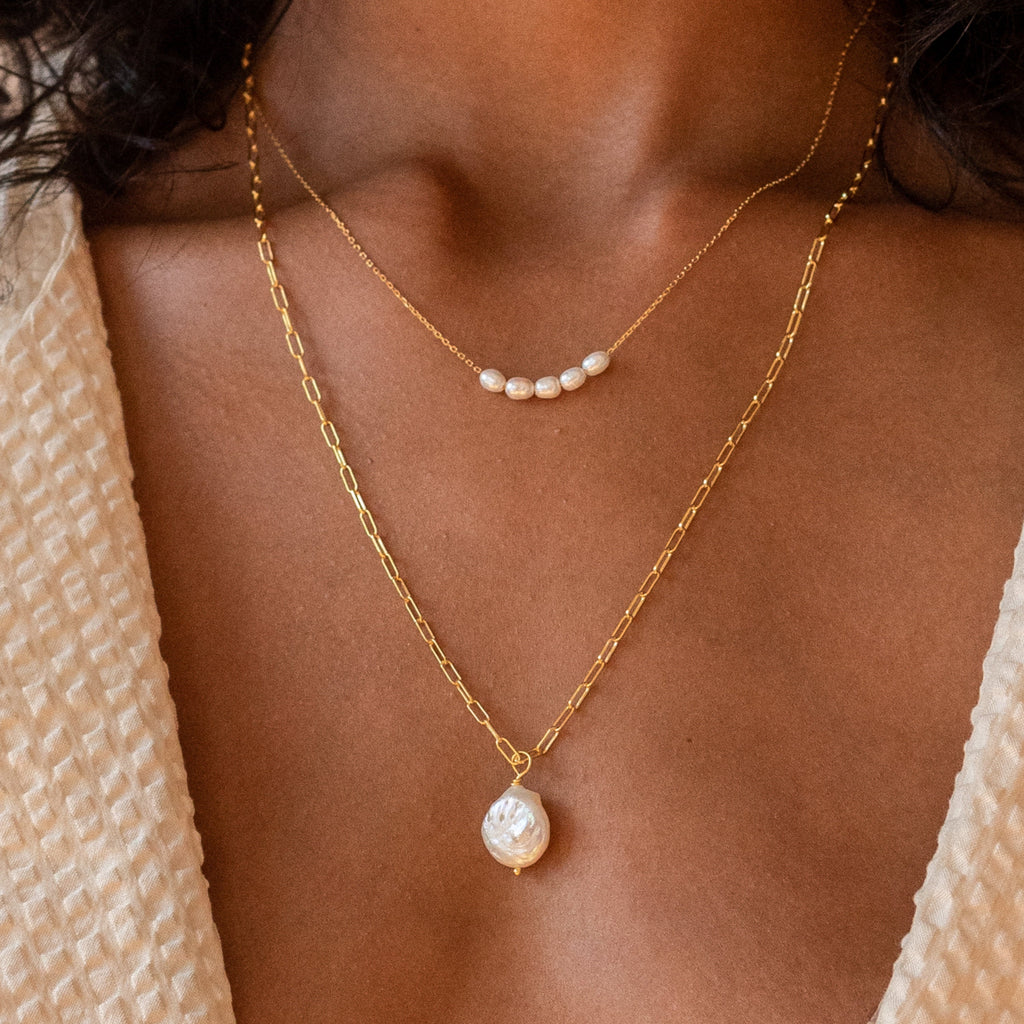 Close up of model wearing gold Pearl Bead Necklace paired with Baroque Pearl Necklace.