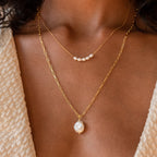 Close up of model wearing gold Pearl Bead Necklace paired with Baroque Pearl Necklace.