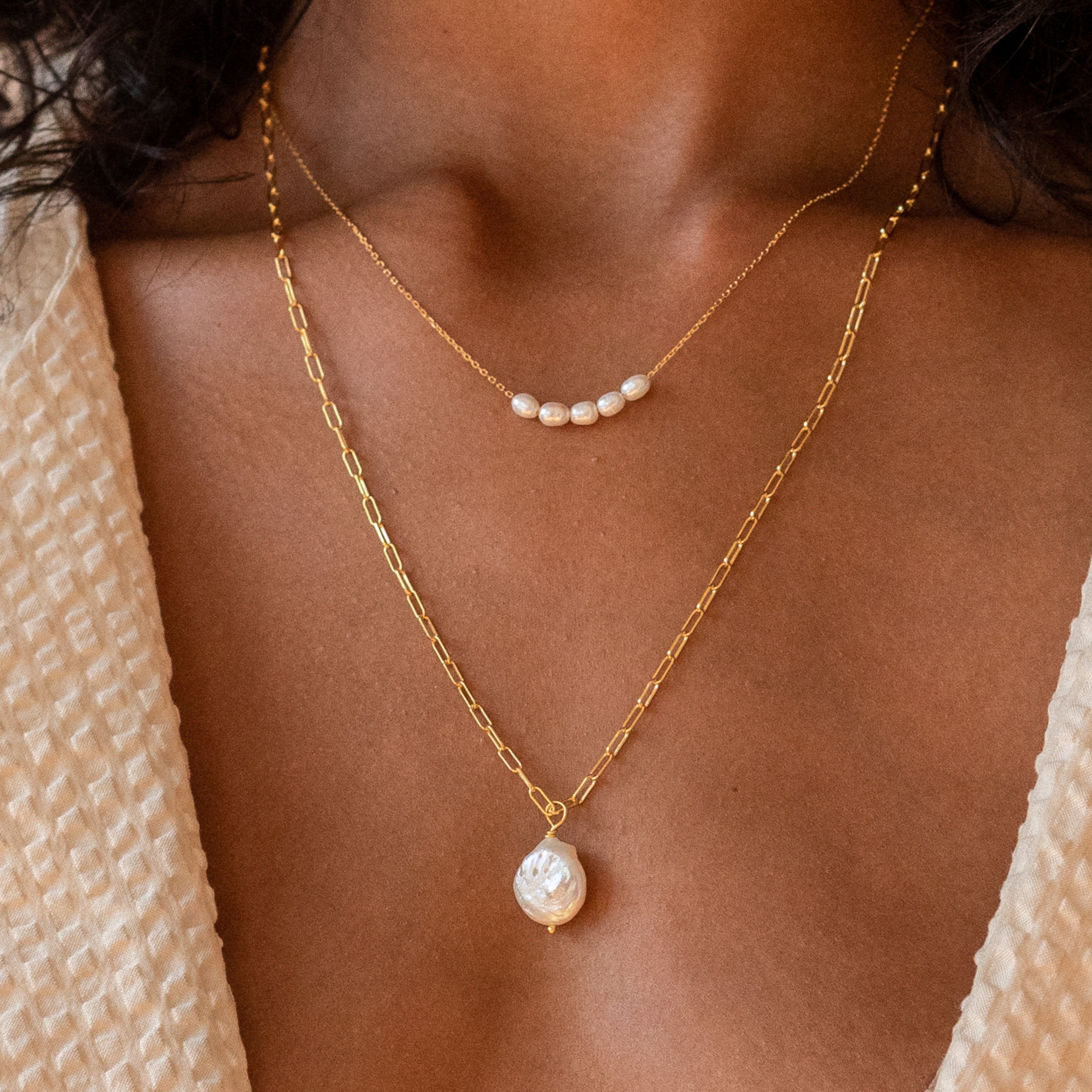 Close up of model wearing gold Pearl Bead Necklace paired with Baroque Pearl Necklace.
