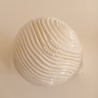 A close up of Pearl Beaded Necklaces in silver, gold, and rose gold on a sculptural wavy surface.