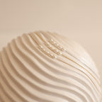 Gold,Silver, and Rose Gold Pearl Bead Necklaces displayed on a textured, wavy white ceramic surface. 
