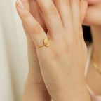 A person wears the Gestures of Love Ring, a thin gold band engraved with a face design that captures subtle symbolic hand gestures in figurative jewelry.
