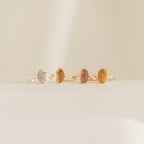 Four Gestures of Love Rings, each engraved with minimalist hand gesture designs, are arranged in a row on a neutral surface and background.