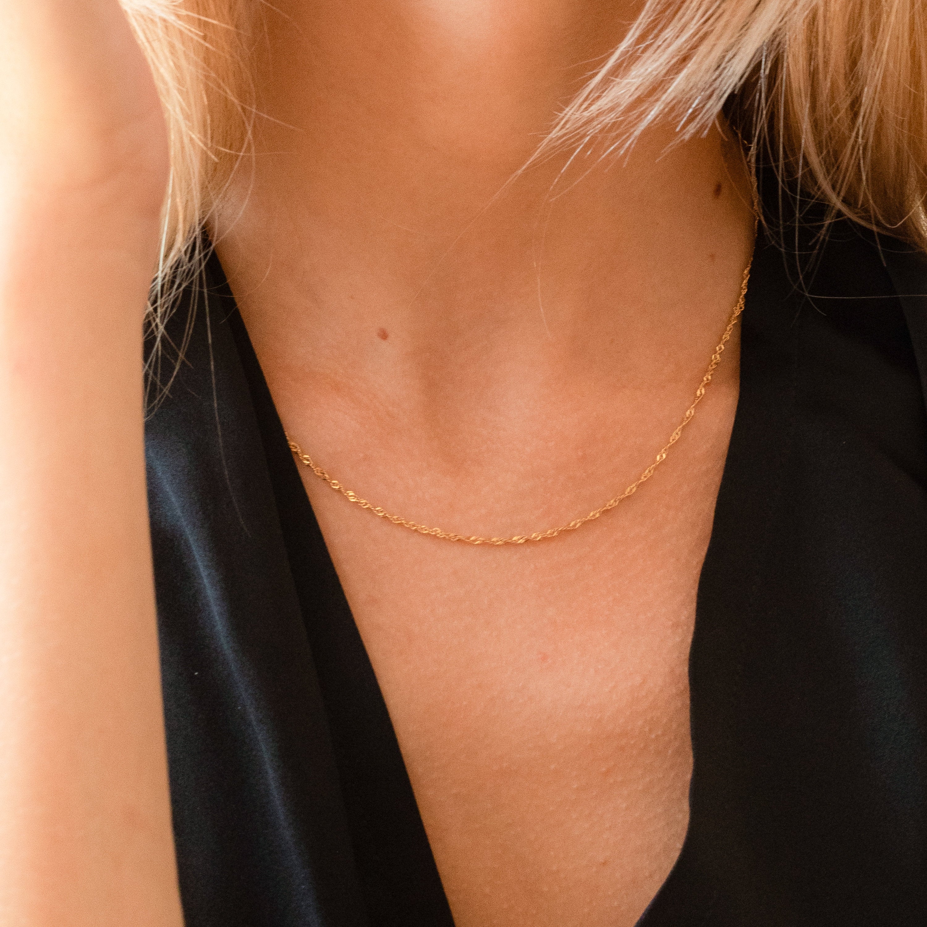 A model wearing the necklace with a black top, showing off its shine and subtle texture.