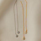 Two pairs of Lux Threader Earrings, one silver and one gold, each featuring a delicate star charm, rest on beige fabric. These chic earrings add a subtle celestial accent to any outfit.