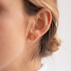 Close-up of a woman's ear wearing a Pave Letter Stud, a small gold earring perfect for those who love minimal jewelry with a personalized touch.