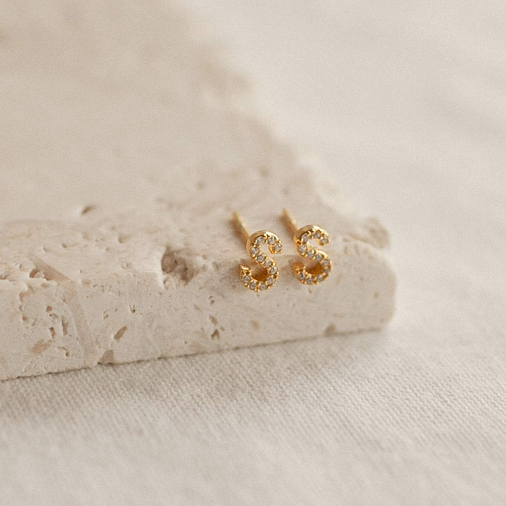 Pave Letter Studs shaped like an S, adorned with sparkling stones on a textured surface—ideal for adding personalized sparkle to your earring collection.
