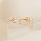 Two Pave Initial Rings, each with a diamond-encrusted "G" and "N," are displayed on a clear surface, highlighting the elegant design of this personalized jewelry.