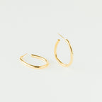 A pair of Anine Oval Hoops is displayed in gold against a plain white background.