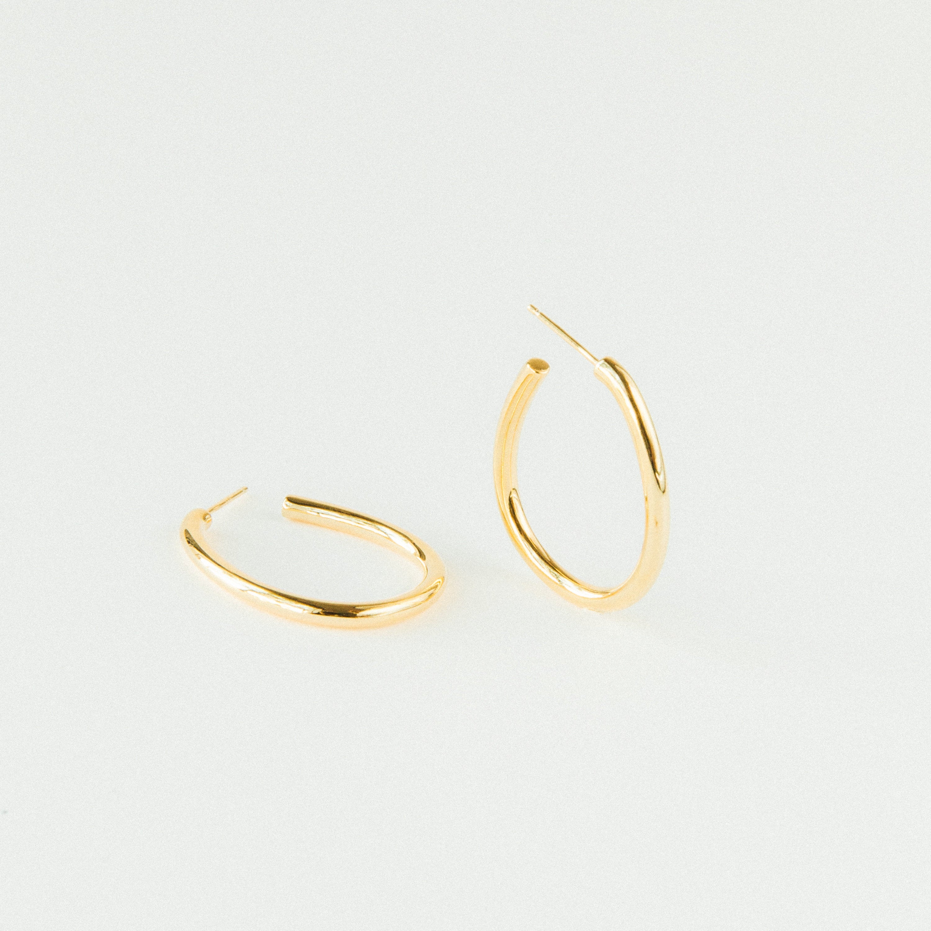 A pair of Anine Oval Hoops is displayed in gold against a plain white background.