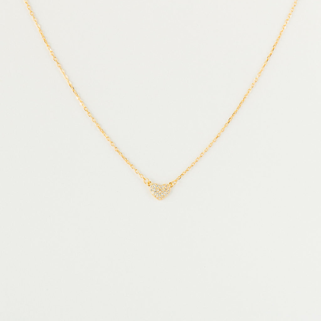 The Pave Heart Necklace features a gold chain with a minimalist heart pendant adorned with tiny clear stones—a delicate accessory perfect for everyday elegance.
