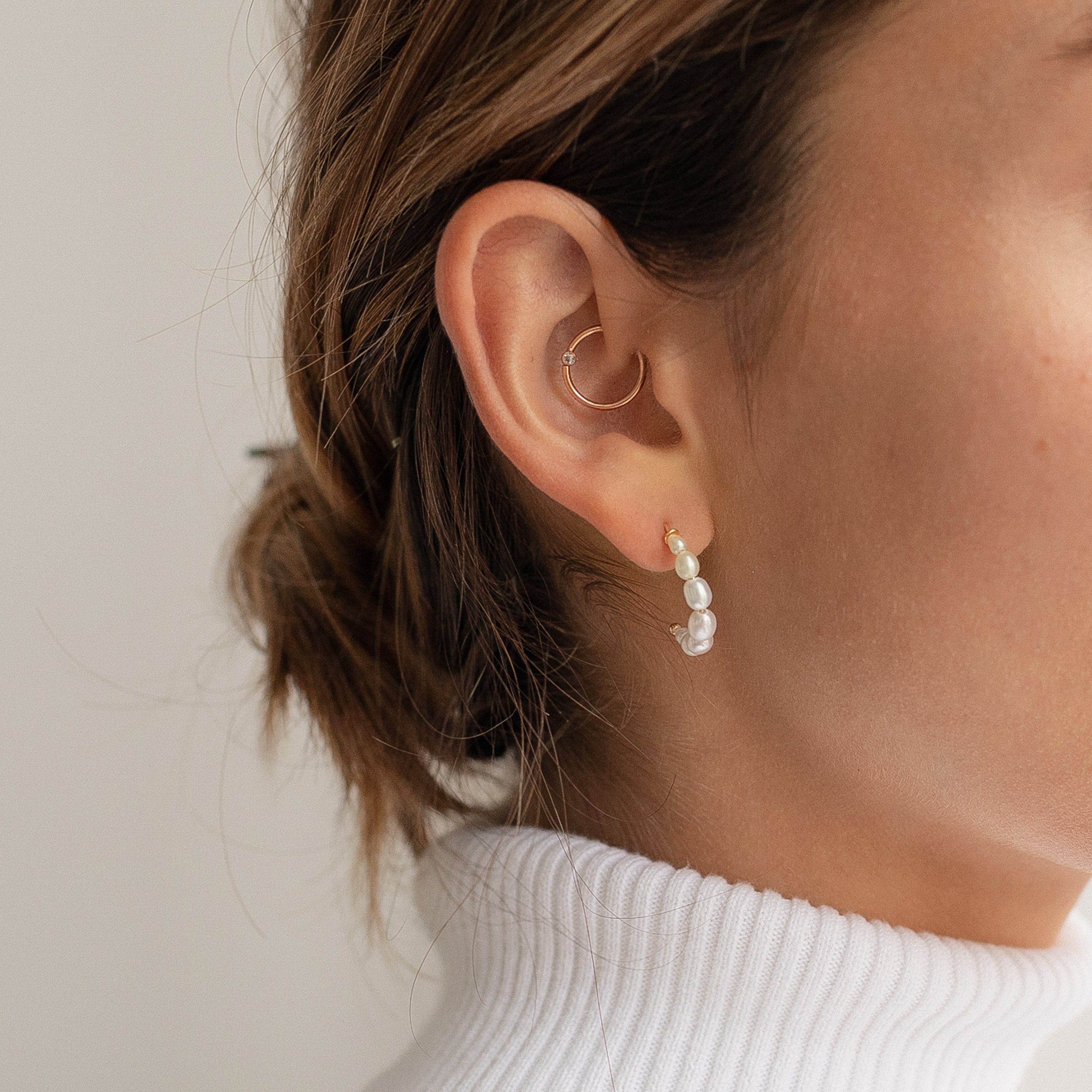 A woman wearing Pearl Hoops, shown from the side against a neutral background—an elegant update to everyday accessories.