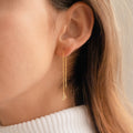 Close-up of a woman wearing Lux Threader Earrings—long gold threaders featuring a delicate star charm—set against a neutral background.