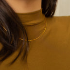 A gold box chain necklace styled over a model's neck