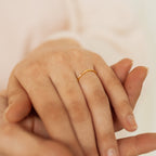 A close-up of a hand wearing the Sprinkle Diamond Ring on the ring finger, gently held by another hand.