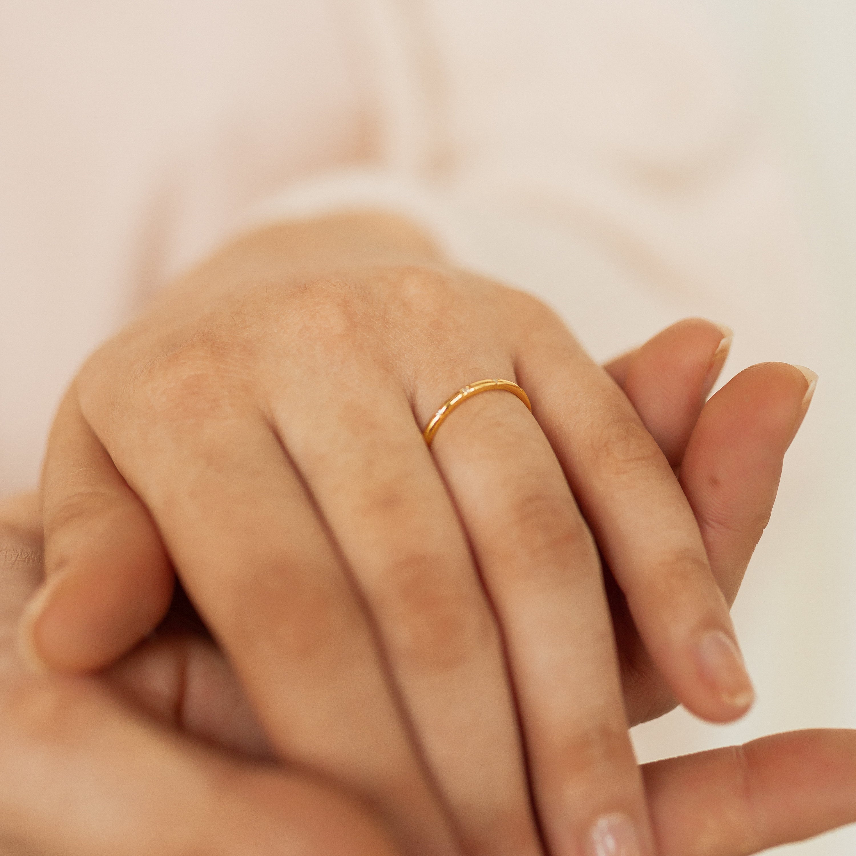 A close-up of a hand wearing the Sprinkle Diamond Ring on the ring finger, gently held by another hand.