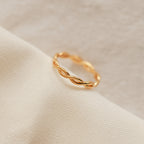 The Braided Ring shines elegantly on a white cloth, ideal for stacking or pairing with your favorite silver band.