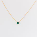 The Malachite Necklace features a gold chain and a small square malachite crystal pendant, shown on a plain white background.