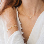 A woman wearing a gold tennis bracelet with pave hearts and the Pave Heart Necklace.