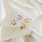 Two pairs of crescent-shaped Zoey Duo Hoops—one silver, one gold—displayed on white fabric; perfect for a chic stacked ear look.