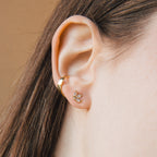 A close-up of an ear adorned with gold hoops and sparkling Arya Petal Studs, paired with a gold stud earring featuring small crystals.