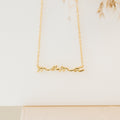 Gold necklace featuring the word “mama” in elegant cursive script, suspended from a delicate chain. Displayed against a clean, neutral background with soft lighting.